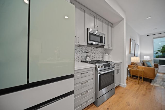 kitchen featuring stainless steel appliances, light hardwood / wood-style flooring, and tasteful backsplash