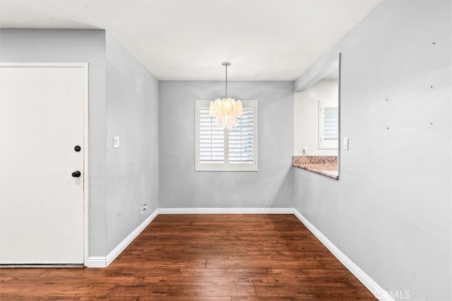 unfurnished dining area featuring a chandelier and dark hardwood / wood-style flooring