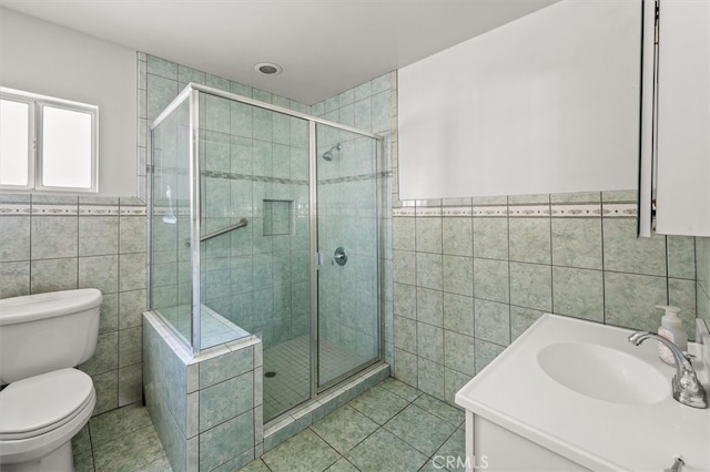 bathroom with vanity, tile walls, toilet, and an enclosed shower