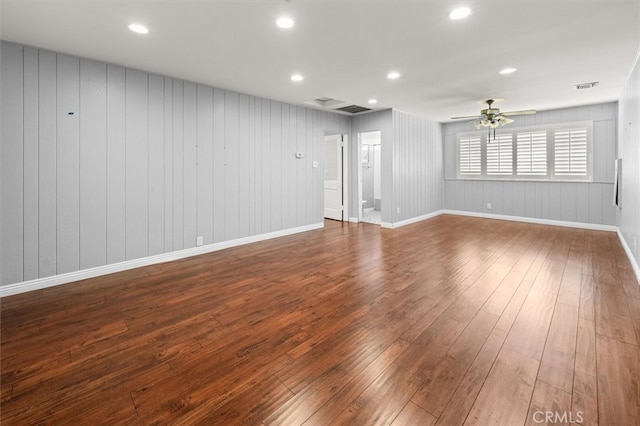 unfurnished room featuring wood walls, ceiling fan, and dark wood-type flooring