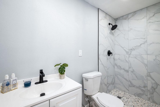 bathroom featuring tiled shower, vanity, and toilet