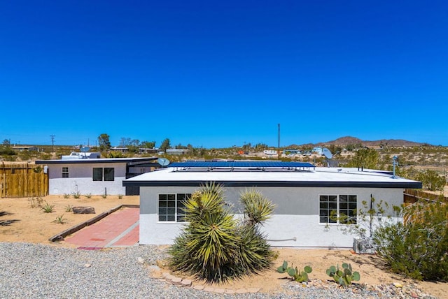 back of property featuring a mountain view and solar panels