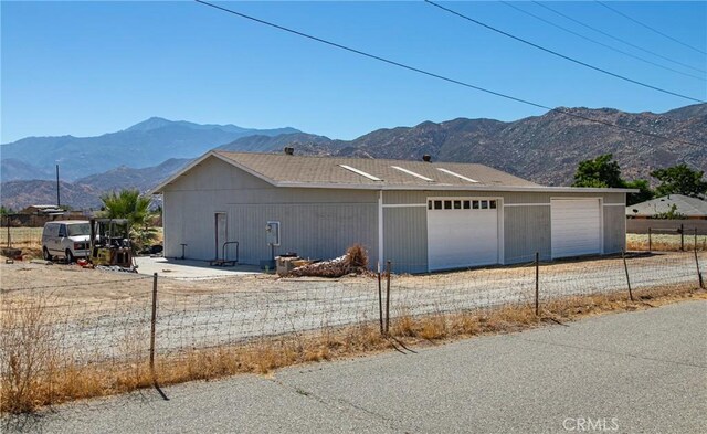 view of side of home with a mountain view, a garage, and an outdoor structure