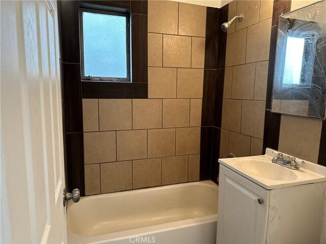 bathroom with a wealth of natural light, vanity, and tiled shower / bath combo