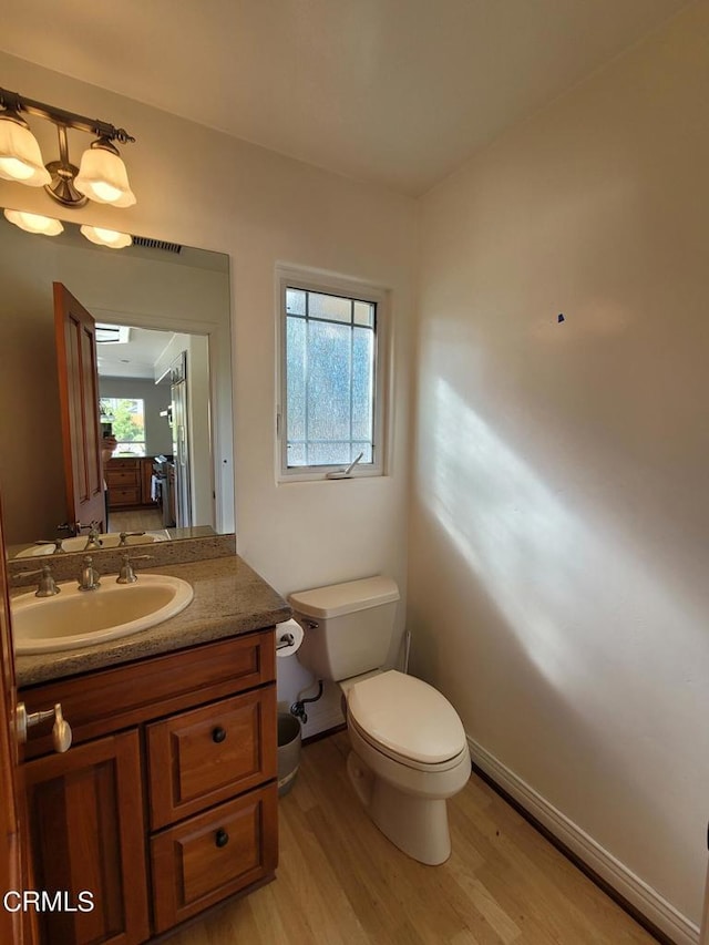 bathroom featuring toilet, vanity, plenty of natural light, and hardwood / wood-style flooring