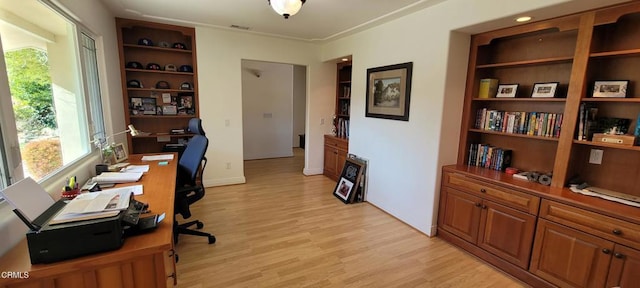 office with built in shelves and light wood-type flooring