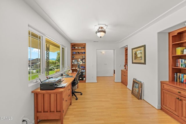 office area with baseboards, built in shelves, and light wood-style flooring