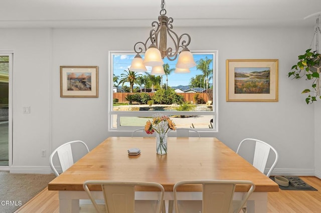 dining space with an inviting chandelier, wood finished floors, and baseboards