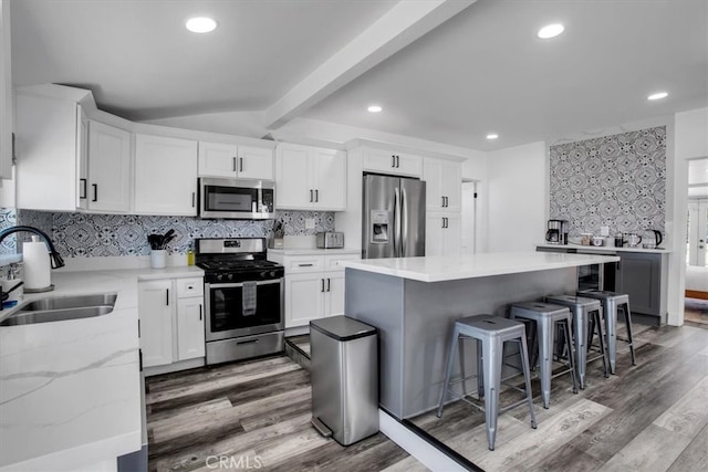 kitchen featuring white cabinets, stainless steel appliances, sink, and a center island