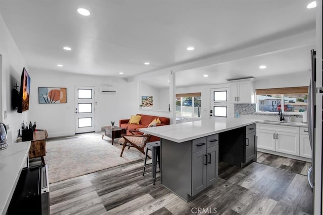 kitchen with a kitchen island, a kitchen bar, white cabinetry, and dark hardwood / wood-style flooring