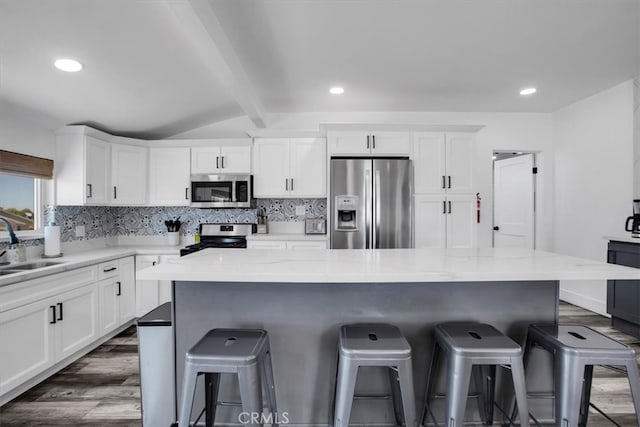 kitchen featuring stainless steel appliances, dark hardwood / wood-style floors, white cabinetry, and a kitchen island