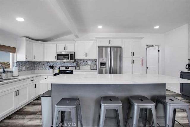 61853 Grand View Cir, Joshua Tree, CA 92252 - kitchen featuring lofted ceiling with beams, a breakfast bar area, stainless steel appliances, white cabinets, and dark wood-type flooring