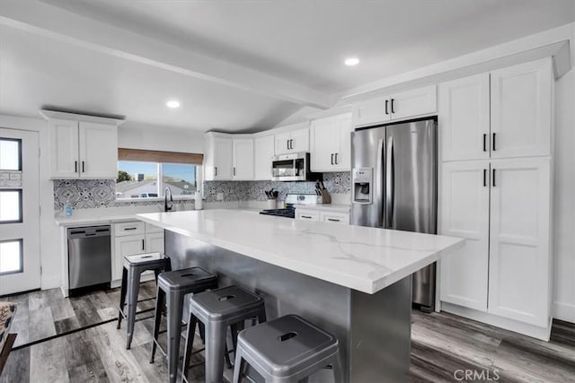 61853 Grand View Cir, Joshua Tree, CA 92252 - kitchen featuring tasteful backsplash, white cabinets, appliances with stainless steel finishes, a kitchen bar, and vaulted ceiling with beams