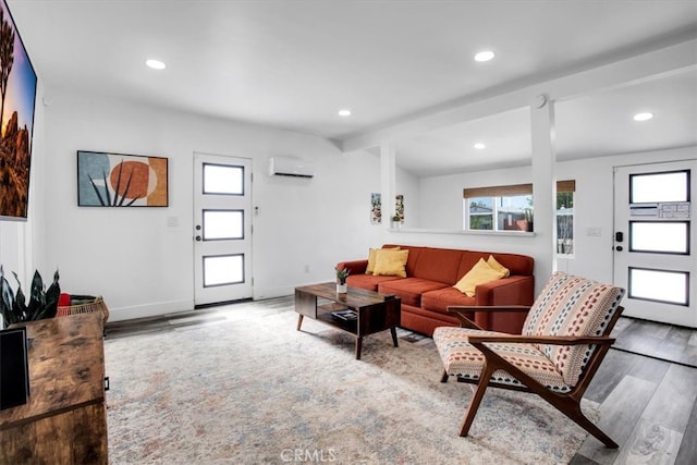 living room with vaulted ceiling with beams, light hardwood / wood-style floors, and a wall unit AC