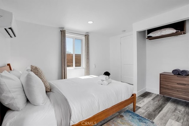 bedroom with wood-type flooring and an AC wall unit