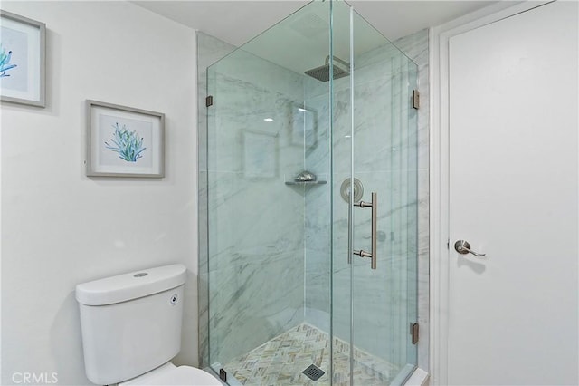 bathroom featuring toilet and a stall shower