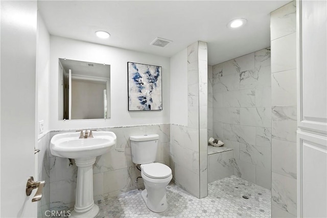 bathroom with tile walls, a marble finish shower, recessed lighting, visible vents, and toilet