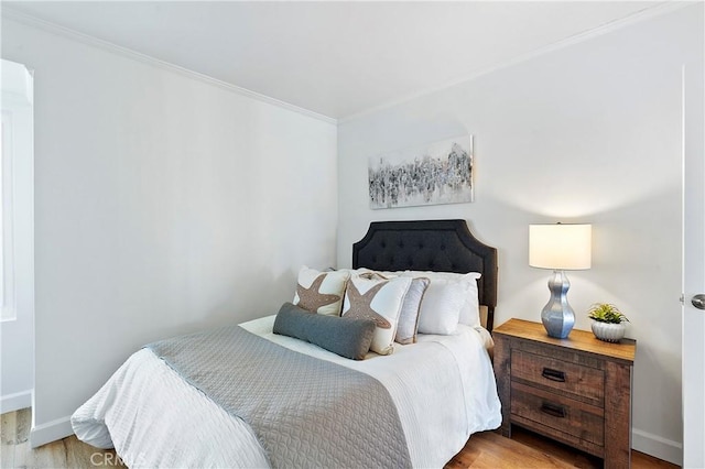 bedroom featuring crown molding, baseboards, and wood finished floors