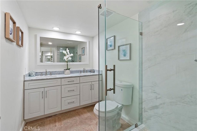 full bath featuring a stall shower, a sink, toilet, and double vanity