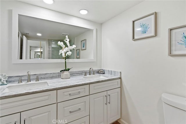 full bath with double vanity, a sink, toilet, and recessed lighting