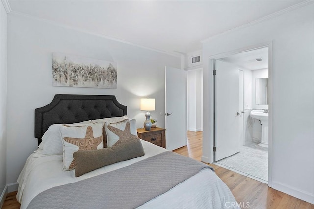 bedroom with baseboards, visible vents, wood finished floors, ensuite bathroom, and crown molding