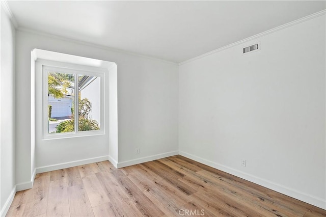 unfurnished room featuring light wood-style flooring, crown molding, visible vents, and baseboards