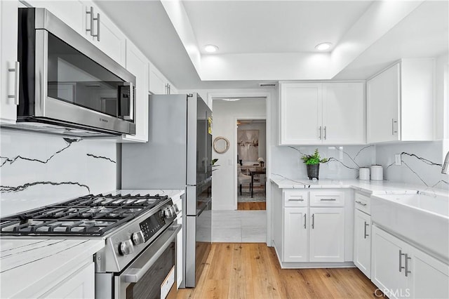 kitchen featuring stainless steel appliances, tasteful backsplash, and white cabinets