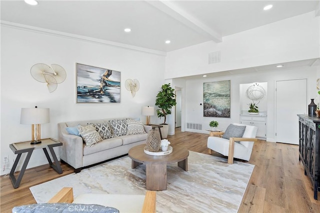 living area featuring beam ceiling, visible vents, and light wood finished floors