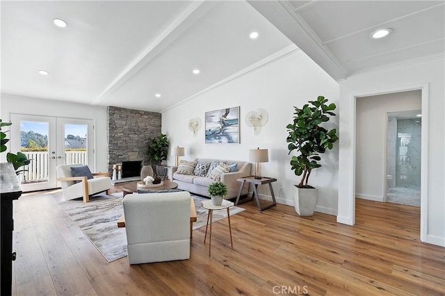 living room with a stone fireplace, french doors, wood-type flooring, and baseboards