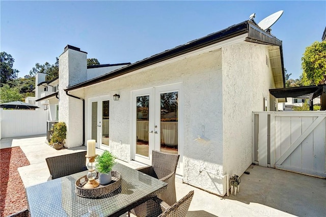 rear view of house featuring fence, french doors, stucco siding, a chimney, and a patio area