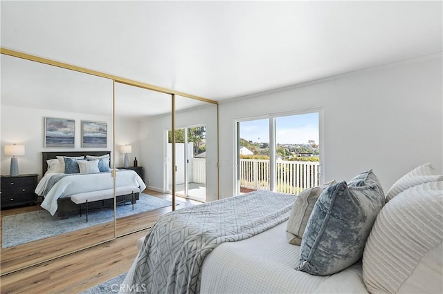 bedroom featuring access to exterior, crown molding, a closet, wood finished floors, and baseboards