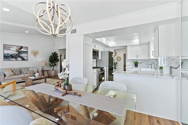 dining space with visible vents, a raised ceiling, light wood-style flooring, a chandelier, and recessed lighting