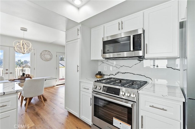 kitchen featuring light stone counters, white cabinetry, appliances with stainless steel finishes, light wood-type flooring, and tasteful backsplash