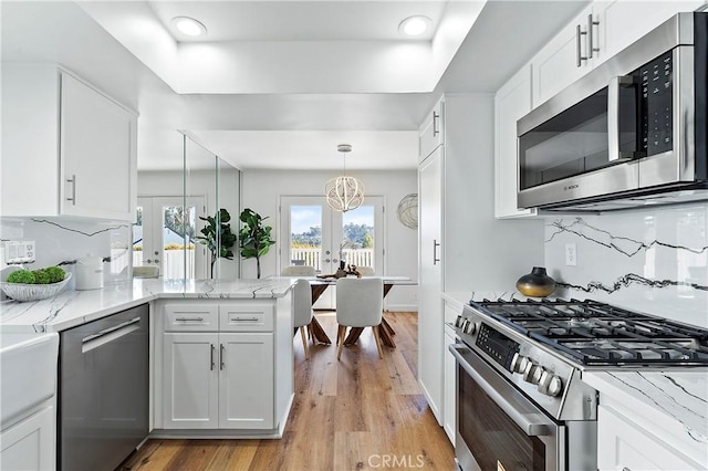 kitchen featuring white cabinets, french doors, appliances with stainless steel finishes, backsplash, and a tray ceiling