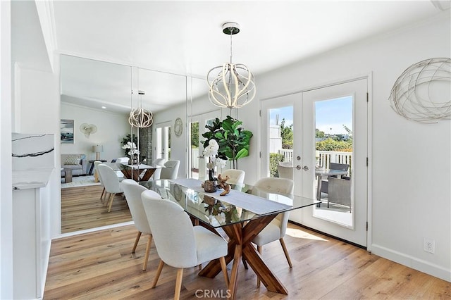 dining space with light wood-type flooring, baseboards, a notable chandelier, and french doors