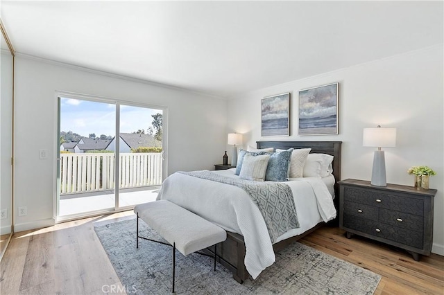 bedroom with access to outside, baseboards, and wood finished floors