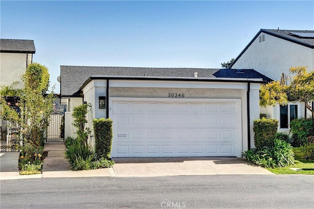 view of front of property with driveway, an attached garage, a gate, and stucco siding