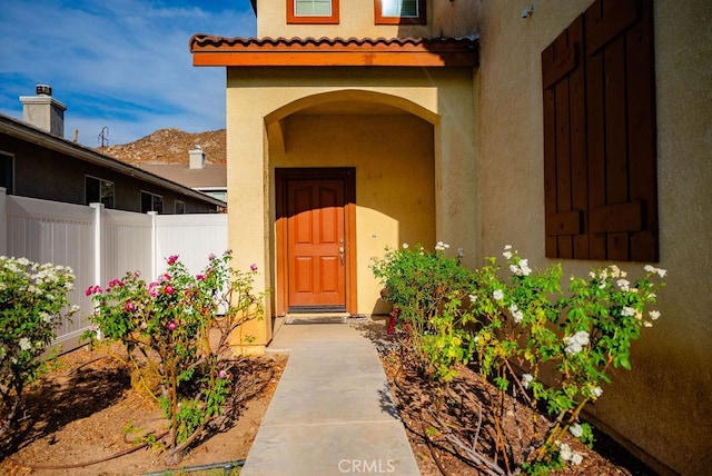 entrance to property with fence and stucco siding