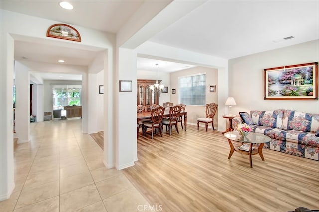 living room with a healthy amount of sunlight, light hardwood / wood-style flooring, and a chandelier