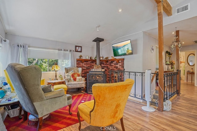 living area with light hardwood / wood-style flooring, lofted ceiling with beams, and a wood stove