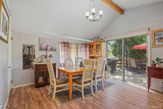 dining space featuring wood-type flooring, lofted ceiling with beams, and a chandelier