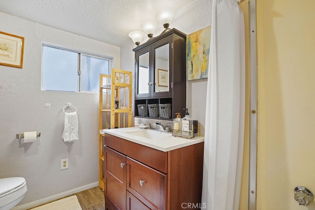 bathroom featuring a textured ceiling, hardwood / wood-style floors, vanity, and toilet