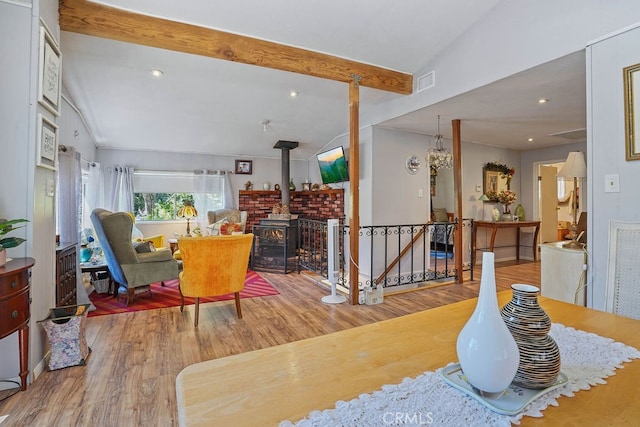 dining room with hardwood / wood-style flooring, lofted ceiling with beams, and a wood stove