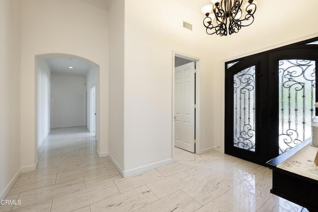 foyer entrance featuring a chandelier, french doors, and a high ceiling