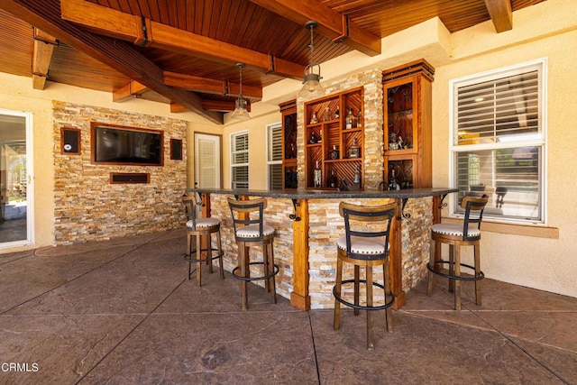 bar featuring beamed ceiling, decorative light fixtures, wooden ceiling, and a wealth of natural light