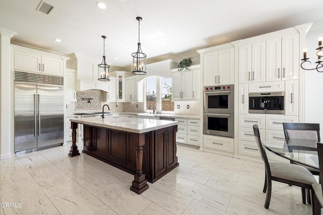 kitchen featuring decorative backsplash, ornamental molding, a kitchen island with sink, and appliances with stainless steel finishes