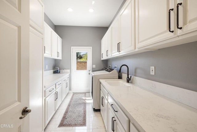 clothes washing area featuring light tile patterned flooring, cabinets, separate washer and dryer, and sink