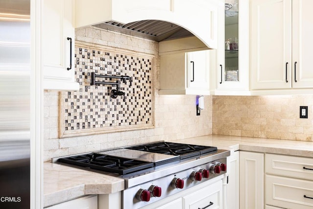 kitchen with backsplash, light stone counters, exhaust hood, white cabinetry, and stainless steel gas stovetop