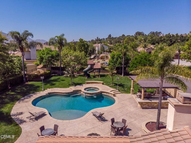 view of pool with a lawn, an in ground hot tub, and a patio