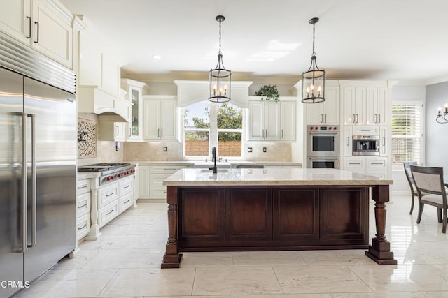 kitchen featuring appliances with stainless steel finishes, a wealth of natural light, a kitchen island with sink, and pendant lighting